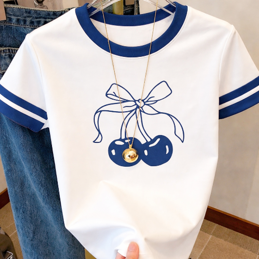 White t-shirt with blue accents and cherry design on a hanger.