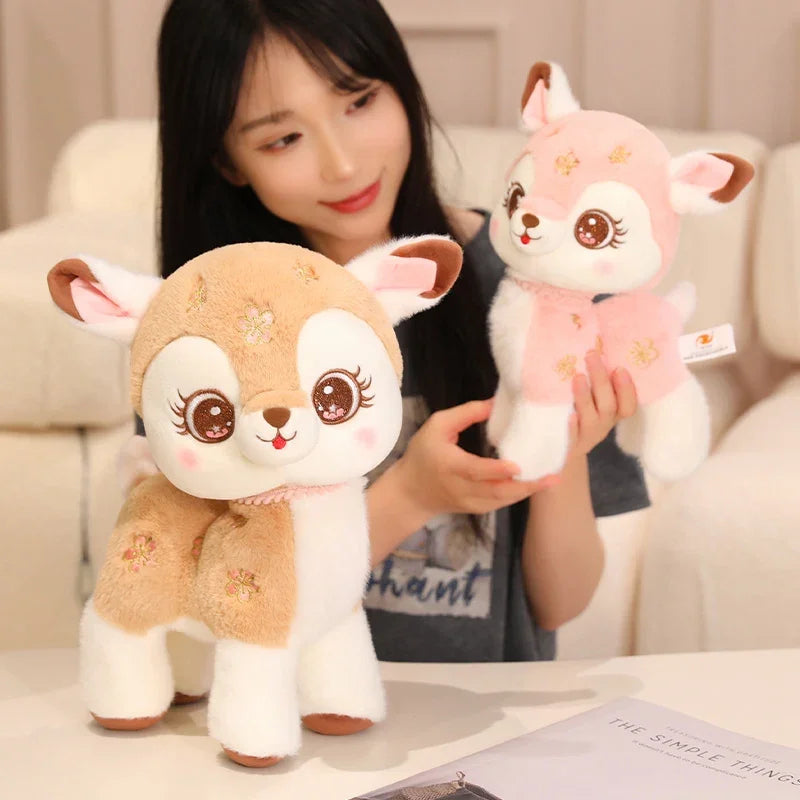 Person holding two plush kawaii deer toys on a light-colored surface.