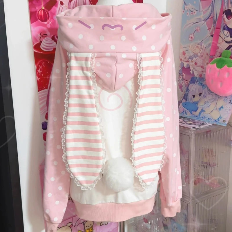 Pink and white polka dot hoodie with striped sleeves on a mannequin against a colorful background.