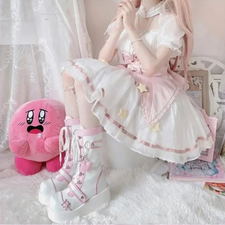 Person wearing a white and pink outfit with kawaii platform boots, sitting on a white chair.