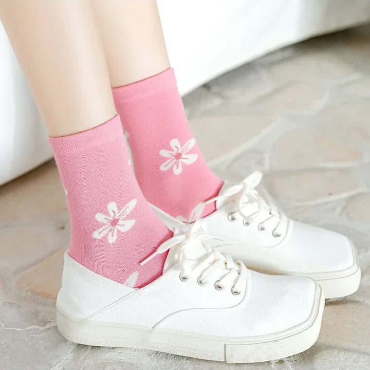 Kawaii Pink socks with white flower designs worn with white sneakers on a light background