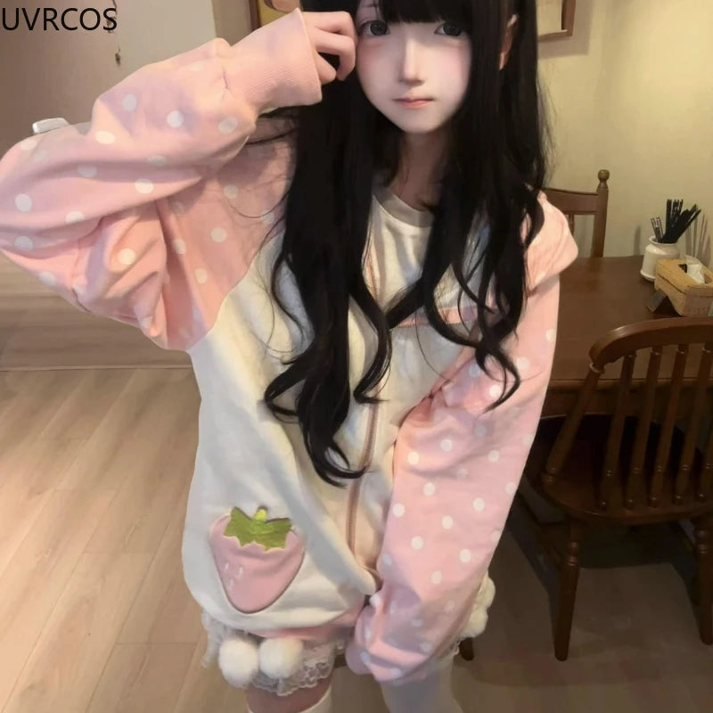 Person wearing a pink polka dot hoodie with a strawberry design indoors.