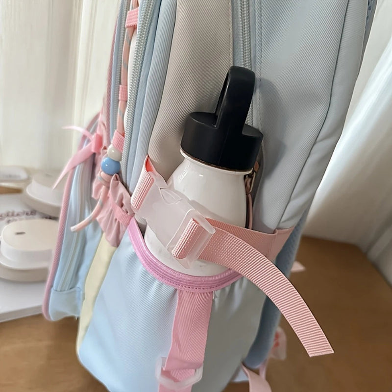 White water bottle with black lid attached to a backpack using a pink strap.