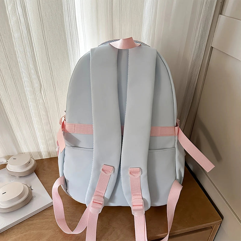 Grey-blue backpack with pink straps on a wooden surface