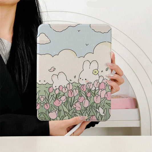 a women holding the Kawaii Tulips & Bunnies iPad Case being displayed on an ipad, bunnies in a tulip meadow with fluffy white clouds and blue sky is on the case itself. the front perspective.