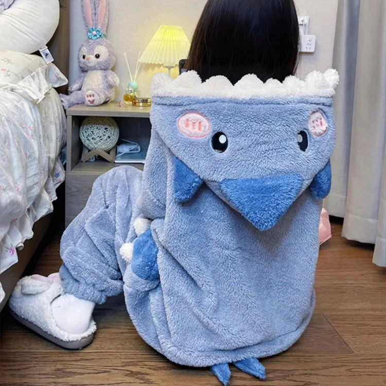 Person wearing a blue shark onesie in a bedroom setting.