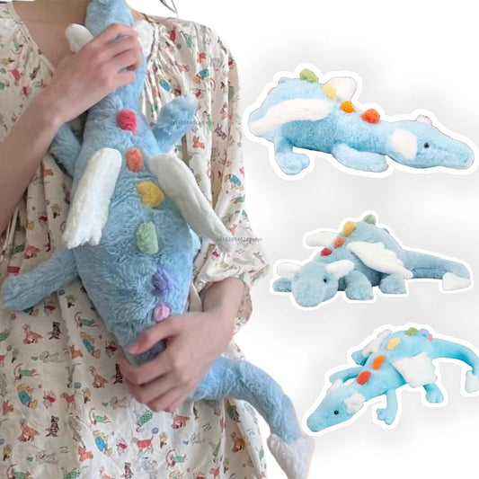 Person holding a blue plush dragon toy with rainbow color accents, surrounded by similar plush toys on a white background.