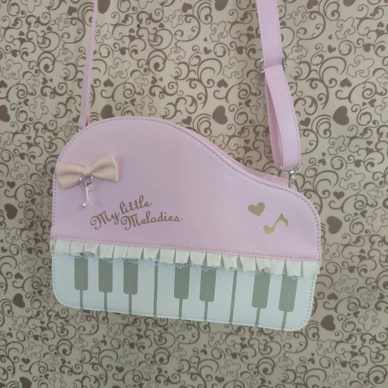 Pink piano-shaped bag with 'My little Melodies' text on a patterned background