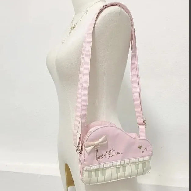 Pink and white kawaii piano bag with a bow on a mannequin against a white background