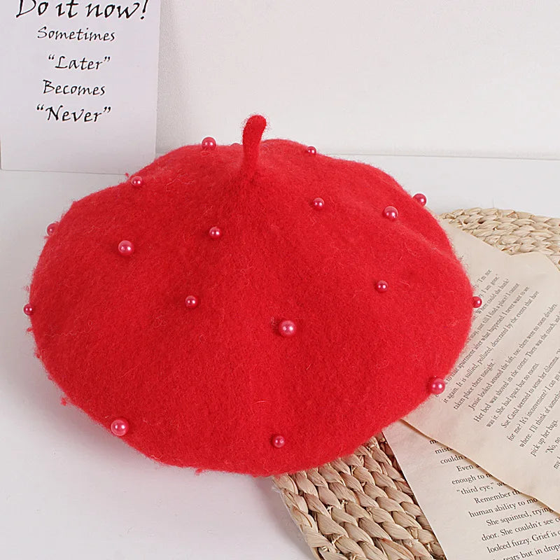 Red beret with pearl-like beads on a surface with text and wicker mat.