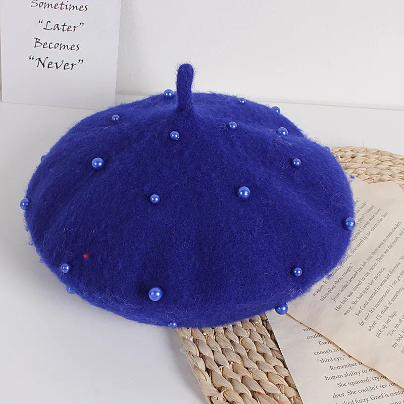 Blue beret with decorative beads on a textured surface