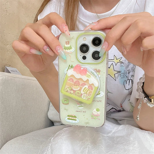 Kawaii Matcha Cake Phone Grip, this is the set that has a case and the stand together, a woman is holding it to display the design.