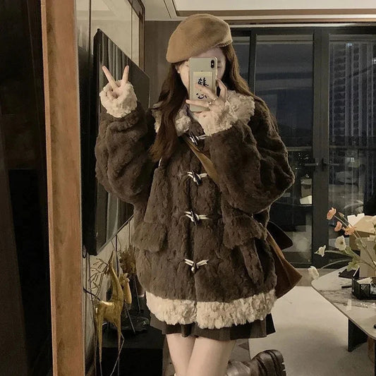 A woman takes a mirror selfie wearing a dark brown shaggy faux-fur jacket with cream faux-fur trim and toggle closures, along with a tan beret and brown boots in a modern indoor setting.