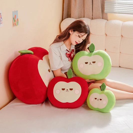 Woman sitting on a couch with large apple-shaped cushions in front of her.