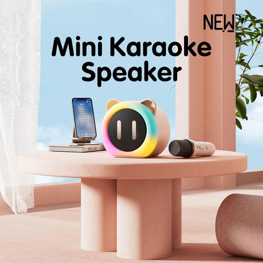 Cute Cat Mini Karaoke Speaker pink edition displayed on a pink table top with a microphone and phone next to it.