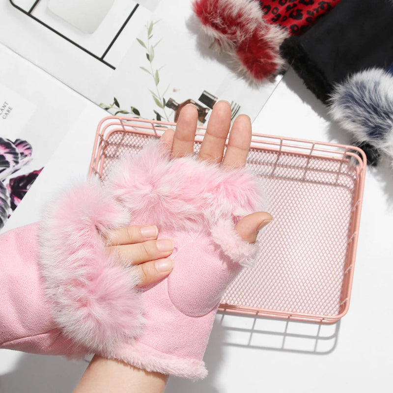 Pink fluffy fingerless gloves worn on a hand with a white background
