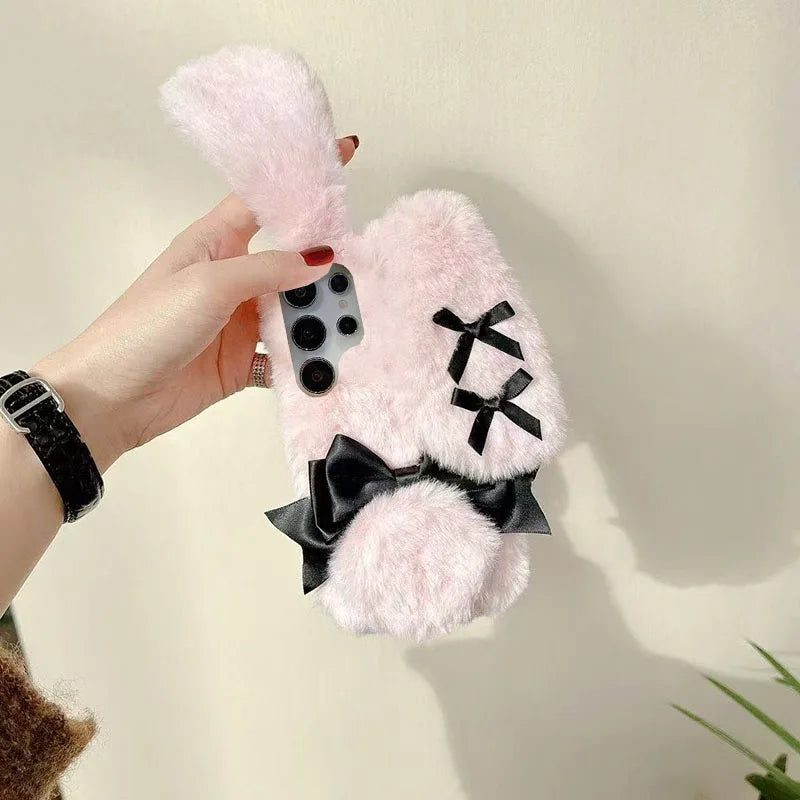 the woman is holding the Kawaii Plush Bunny Samsung Phone Case to display the back of the case , showing off the floppy pink bunny ears.