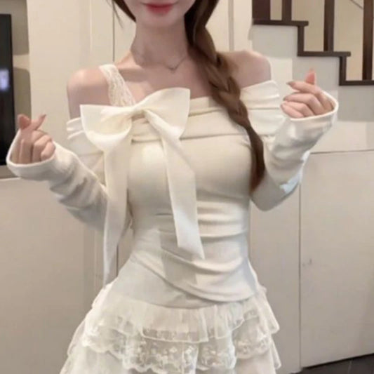 Girl wearing white off shoulder top making hearts with her fingers while standing infrong of a wall and part of a staircase.