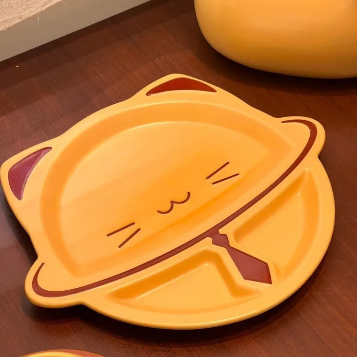 A yellow cat-shaped divided plate with dark red accents, shown on a dark brown wooden tabletop.