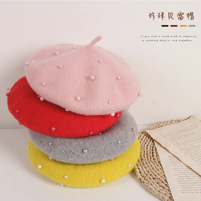 Stack of colorful berets with pearl embellishments on a light background