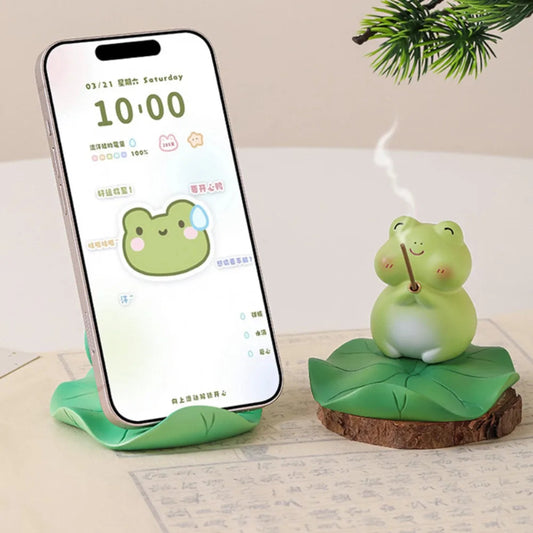 Smartphone on a stand with a frog-themed device next to it on a light surface.