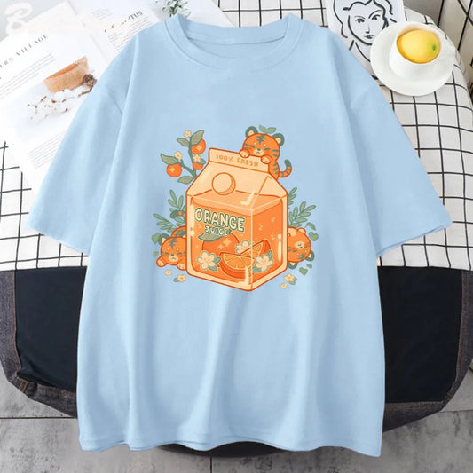 A blue t-shirt with an illustration of a tiger character drinking orange juice from a carton, surrounded by orange slices and green leaves.