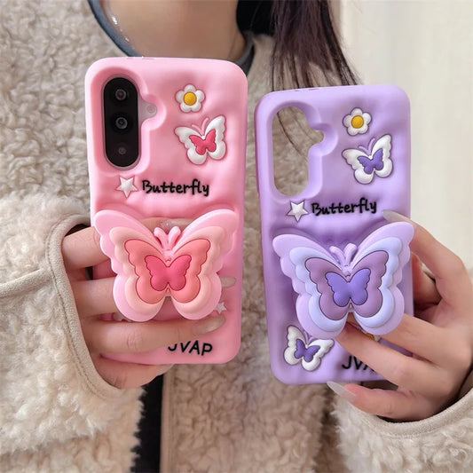 This image is showing two designs that are available for the Kawaii Butterfly Samsung Phone Case, one option is the pink design with a large 3D butterfly in the middle which is a phone grip with smaller butterflies around it and some white flowers, the other option is of this the same design but in purple.