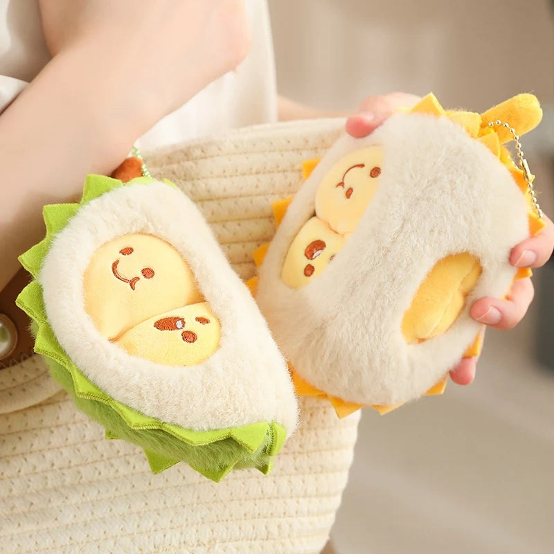 Two plush toys shaped like pieces of durian with faces held by a person.