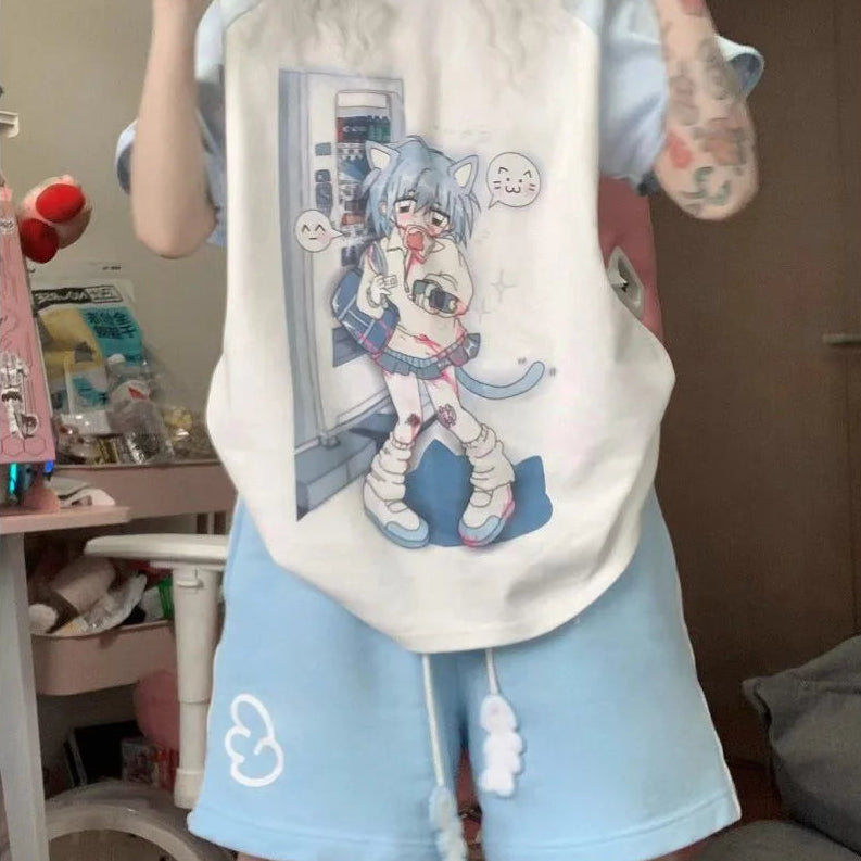 A person wearing a light blue and off-white raglan t-shirt with a large anime cat graphic, paired with matching light blue shorts, standing in a bedroom setting.