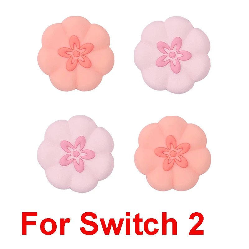 Four pink and peach-colored floral-shaped thumb grips with 'For Switch 2' text on a white background