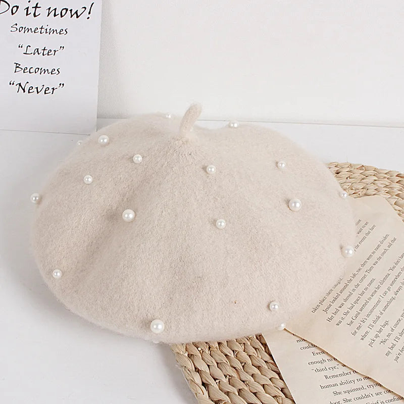 Beige beret with pearl embellishments on a white surface with a motivational quote card.