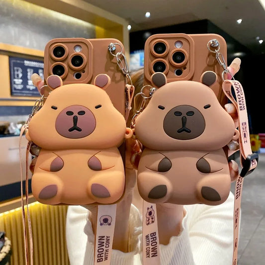 Two Capybara-shaped kawaii phone cases with lanyards in a store setting