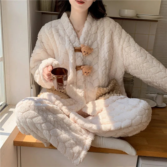 Person wearing a white fluffy robe with teddy bear buttons, sitting on a wooden stool indoors.