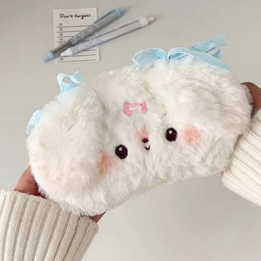 Plush white puppy pencil case with a blue bow held by a person.