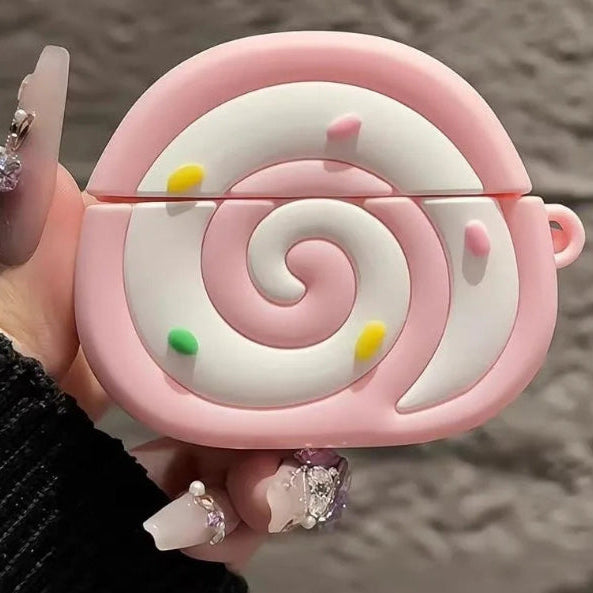 Pink swiss roll shaped air pod case held by a hand with a blurred indoor background