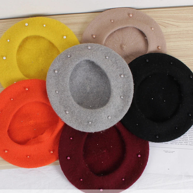 Set of colorful felt hats with bead embellishments on a wooden surface.