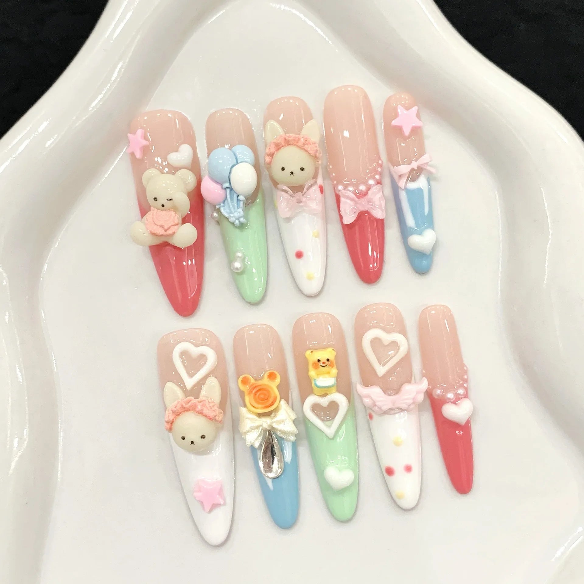 Decorative false nails with cute designs on a white dish