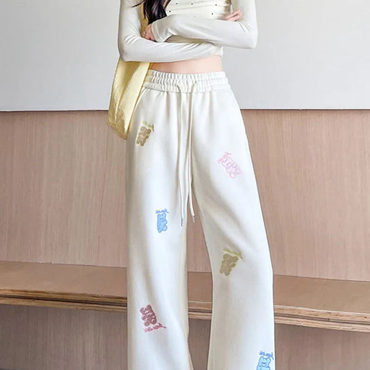 White pants with colorful designs worn by a person indoors.