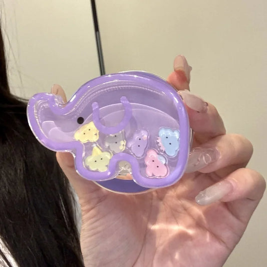 a woman holding a kawaii cute elephant quicksand phone grip , this is in the color purple with colorful elephant faces inside