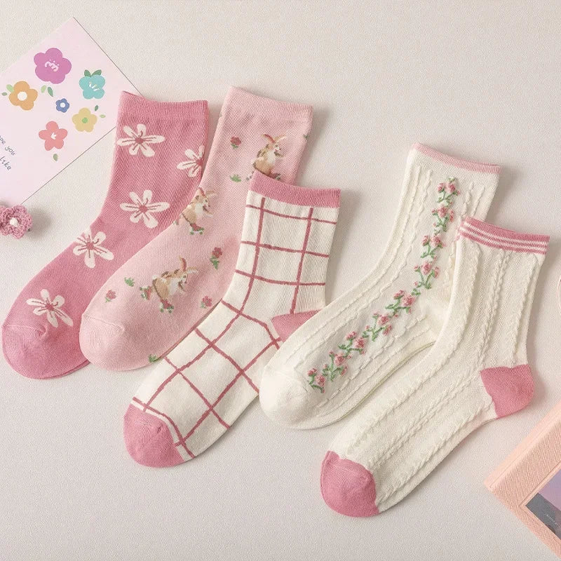 Set of pink and white socks with floral and grid patterns on a light background