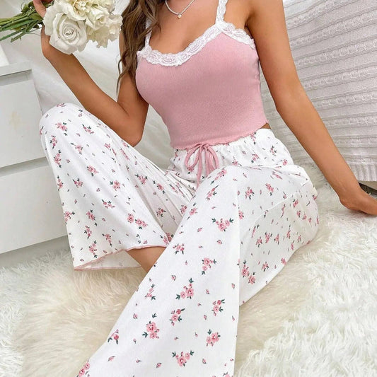 Woman wearing a pink top and white floral pants sitting on a white surface.