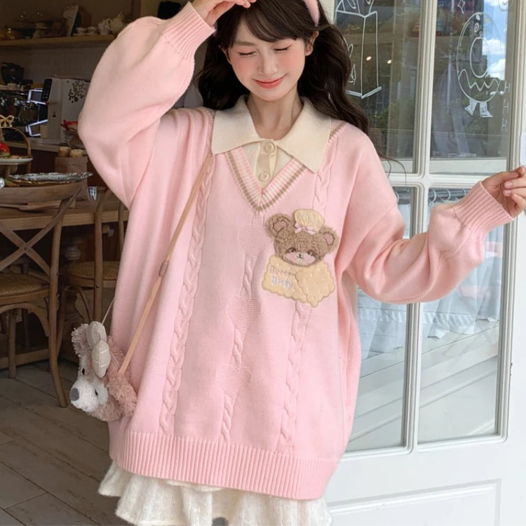 Woman wearing a pink sweater with a bear design, standing in a room.