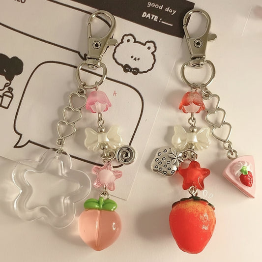Two decorative keychains with fruit and bow designs on a white background.