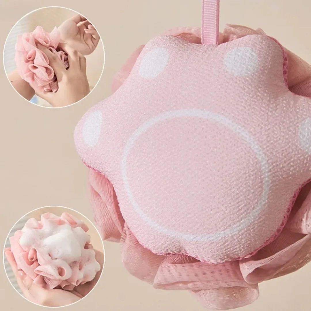 Pink bath pouf with a close-up of hands using it and the resulting foam on a beige background.