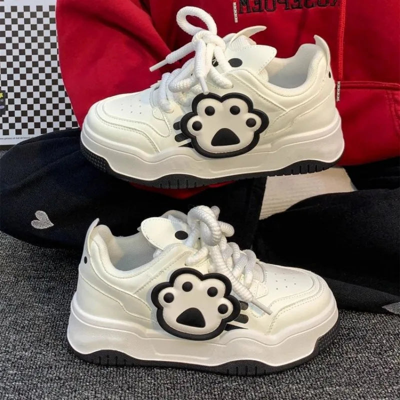 White sneakers with a paw print design on a checkered floor.