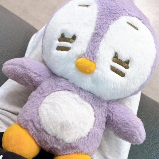 Sleepy light purple penguin plushie resting on someone's lap