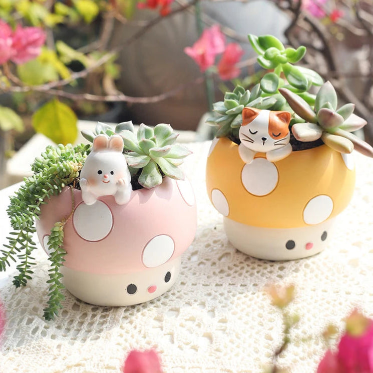 Two cute mushroom-shaped planters with animal figures on a textured surface.
