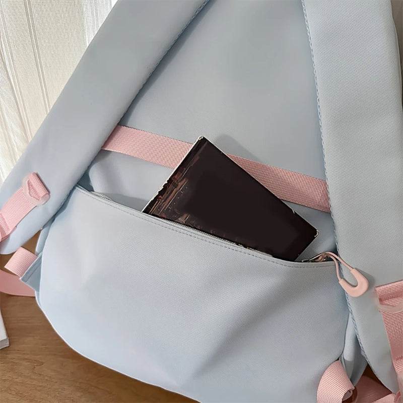Blue backpack with pink straps and a black item inside on a wooden surface.