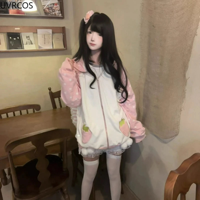 Person wearing a pink and white hoodie with strawberry design in a room with wooden furniture.