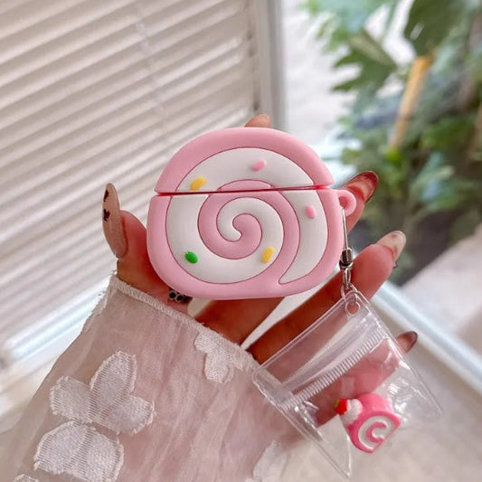 Pink swiss roll shaped air pod case held by a hand with a blurred indoor background